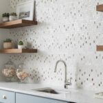 White mosaic tile backsplash with textured surface and warm wooden shelves.