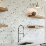 White mosaic tile with green glass accents, textured surface, in a bright kitchen setting.