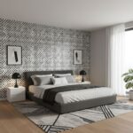 A bedroom featuring a black and white geometric patterned tile accent wall, with a sleek gray bed, white bedding, and minimal.