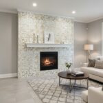 A close-up of a contemporary living room fireplace with a white mosaic tile wall, featuring a sleek black fireplace insert an.