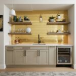 Bright beige kitchen with wooden shelves and yellow tile backsplash, featuring a black faucet and wine cooler.
