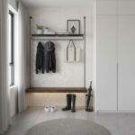 A clean, white textured tile wall with subtle geometric patterns, complemented by black hooks, shelf, and accessories for a m.
