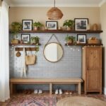 Gray subway tile wall with wooden shelves, framed photos, and potted plants, creating a cozy and stylish entryway.
