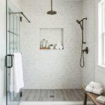 Bright white mosaic tile shower with built-in niche and bronze fixtures.