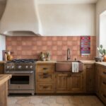 A close-up of a kitchen wall featuring terracotta-colored square tiles with a matte finish, complemented by rustic wooden cab.