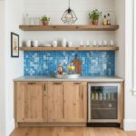 Bright blue mosaic tile backsplash with a wooden shelf and cabinetry, modern kitchen decor.