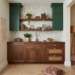 Green wall tiles with a textured, mosaic pattern complement the wooden cabinetry and open shelves.