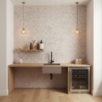 Pink speckled tile wall with textured surface, black faucet, and minimalist decor. Compact wine fridge and wooden countertop.